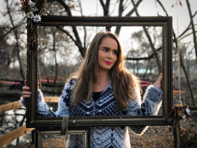 Creative portrait of young woman holding wooden frame, artistic composition