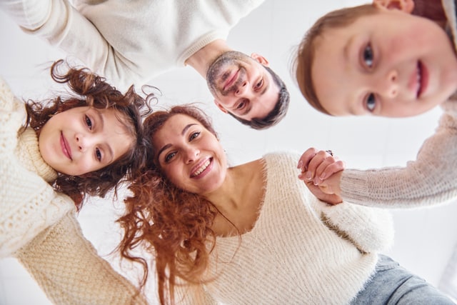 Happy family looking down at camera, joyful moment captured from below